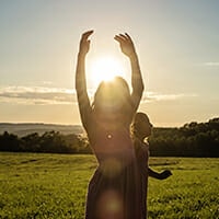Woman with arms raised in sunset field — Treasure Valley horse photography session