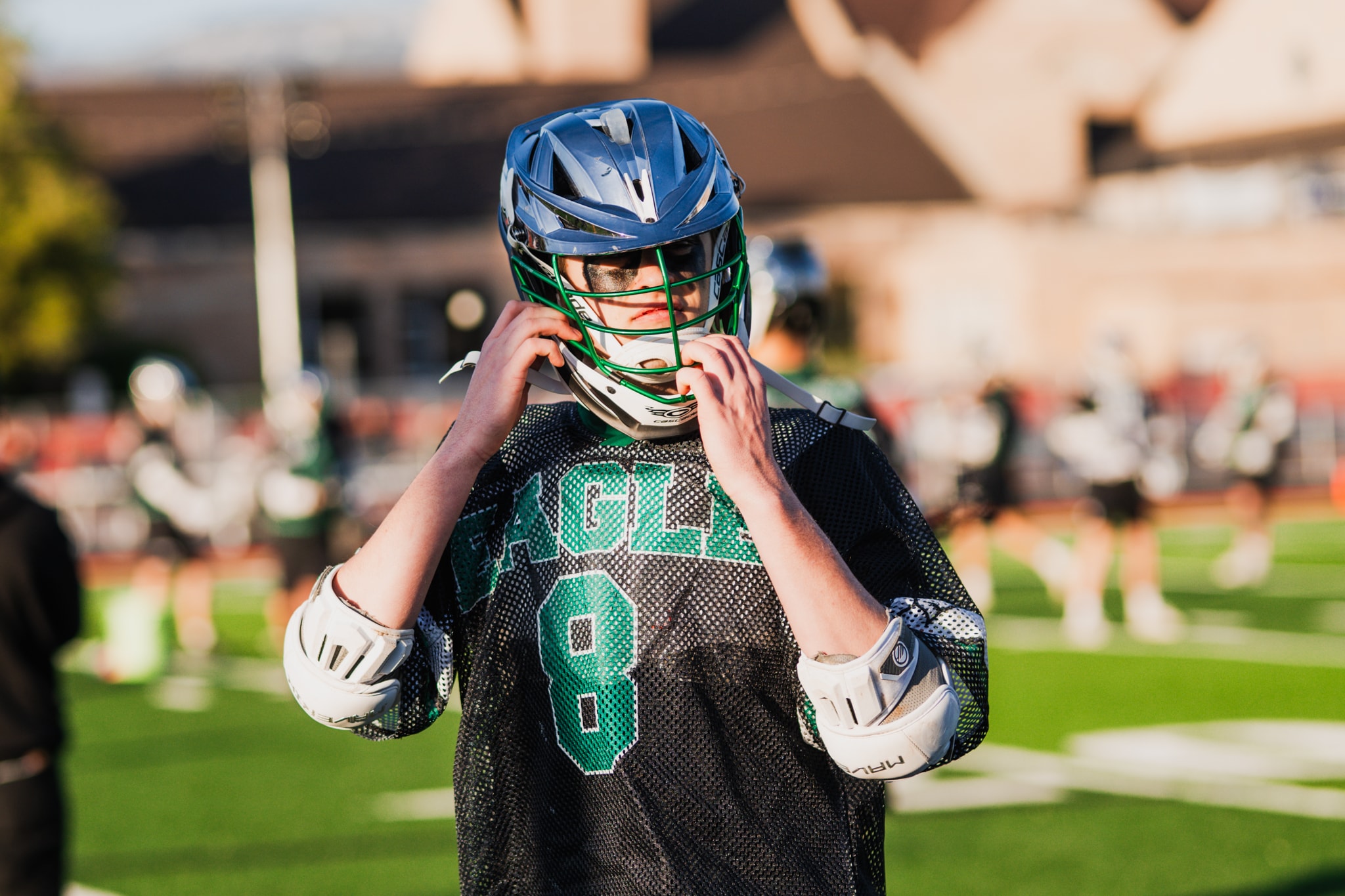 Young lacrosse player adjusting helmet — youth sports photographer Idaho