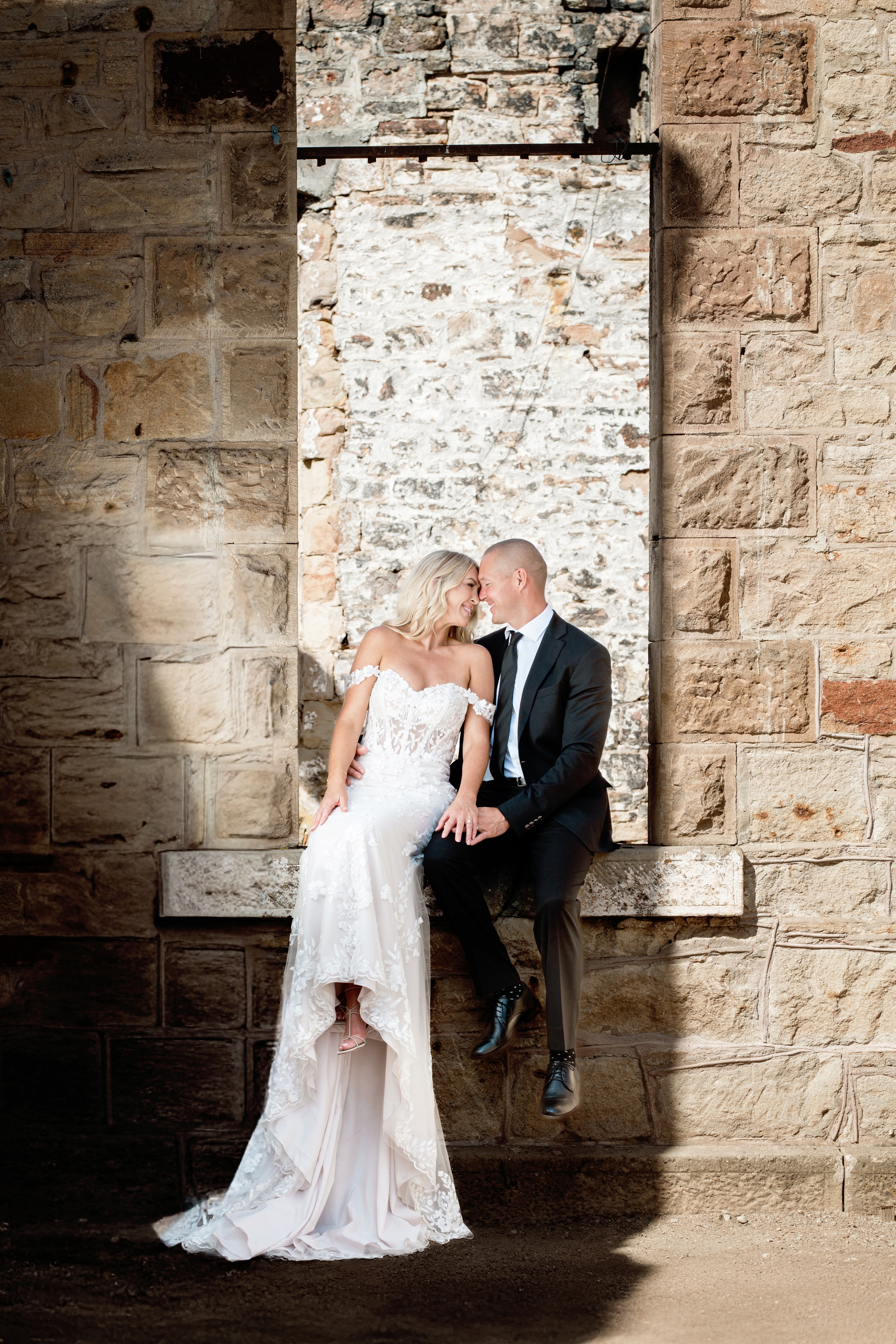 Bride and groom sitting together on stone wall — Treasure Valley wedding photography
