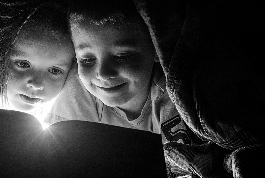 Boy and a girl reading together in black and white