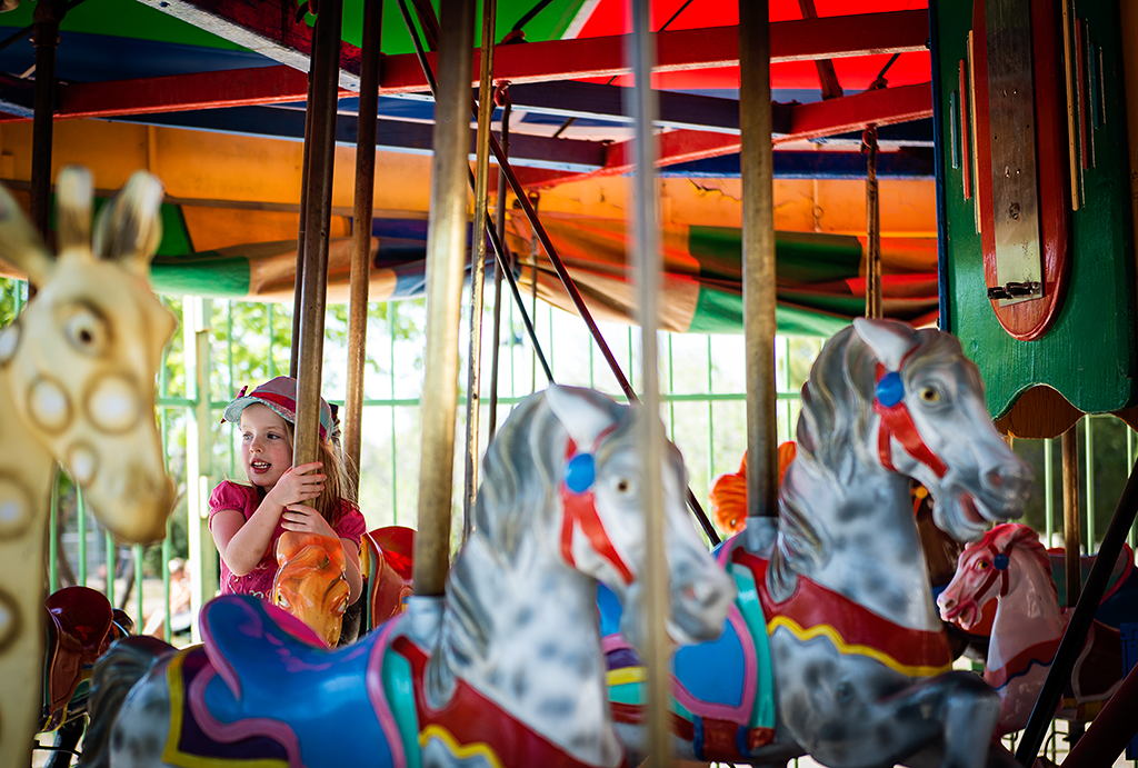Little girl on spinning colorful carousel