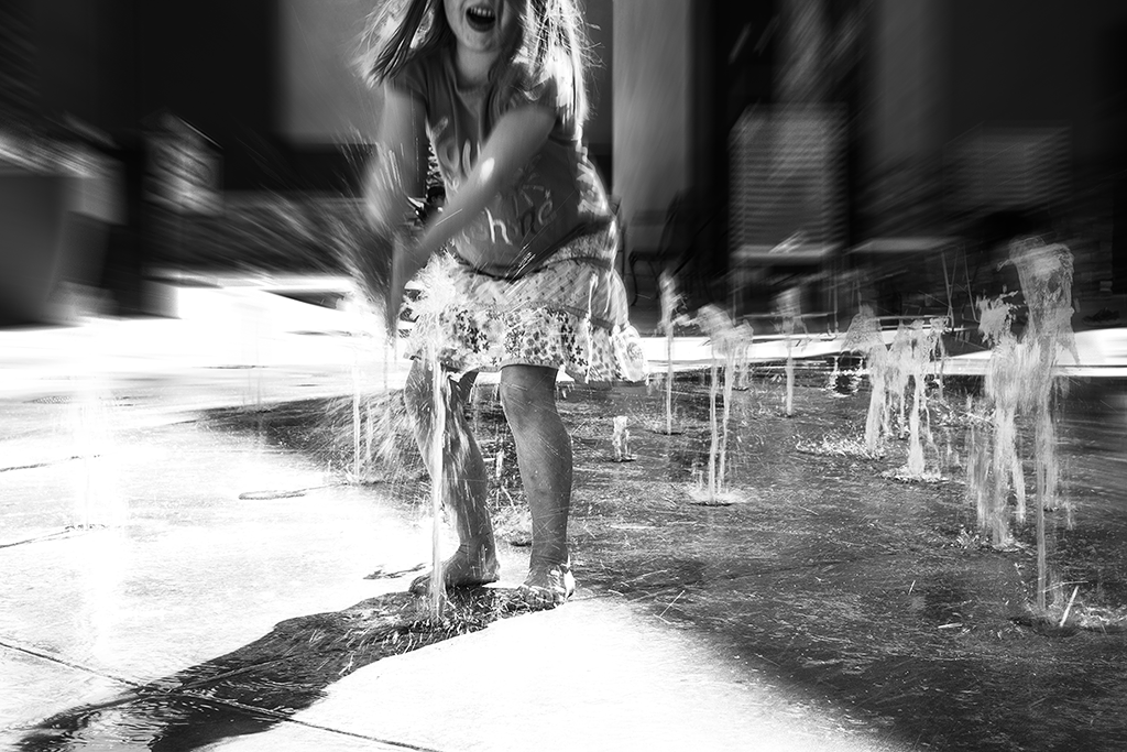 Black and white photograph of little girl jumping in water
