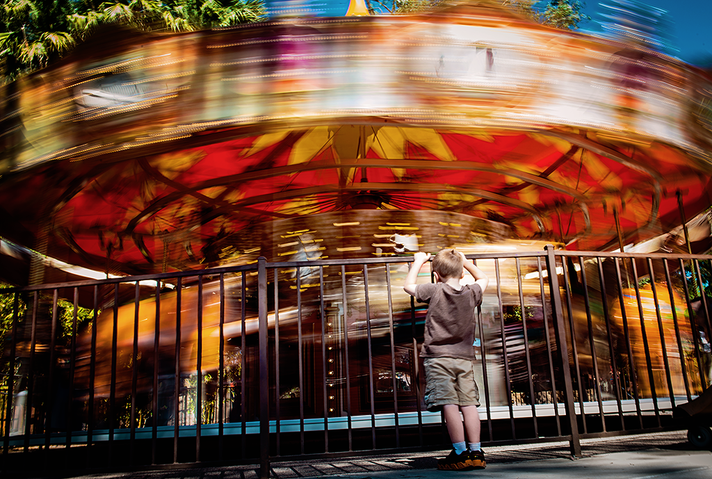 Boy watching carousel spinning.
