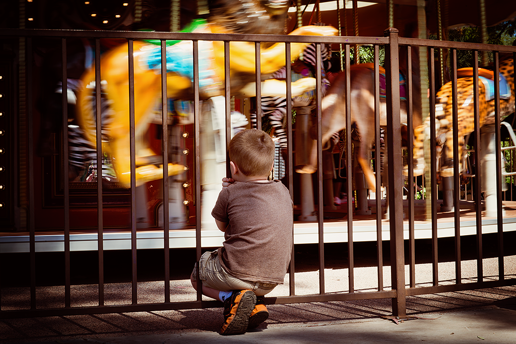 Boy watching carousel spinning.
